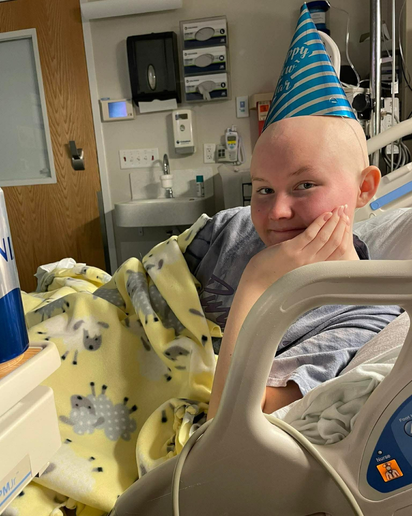 A student in a hospital bed wearing a birthday hat. 