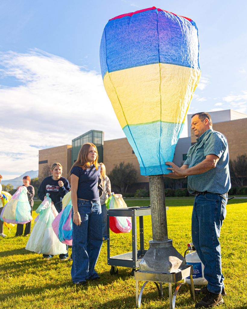 Students lined up to launch their balloons while the teacher is about to let one balloon go. 