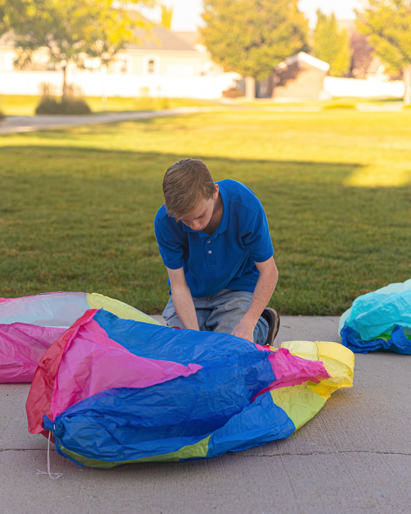 A student kneeling, working on their hot air balloon project. 