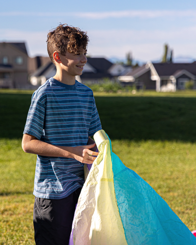 A student smiles as they hold their hot air balloon. 