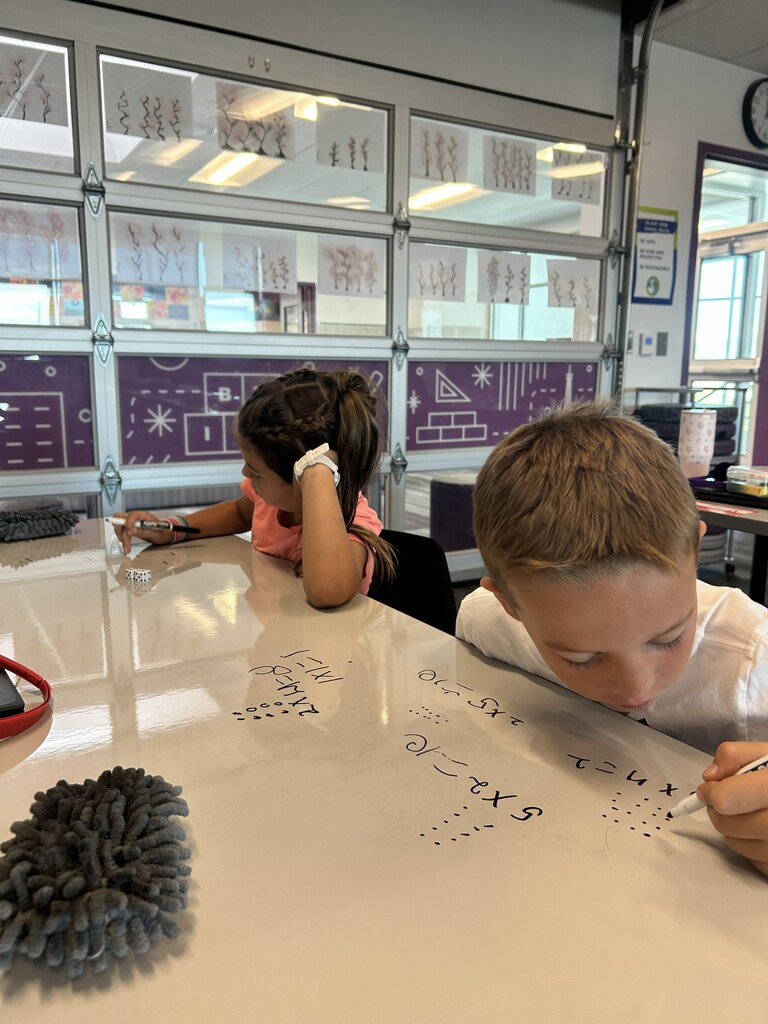 a boy drawing dots and a girl in a pink shirt holding a dry erase marker