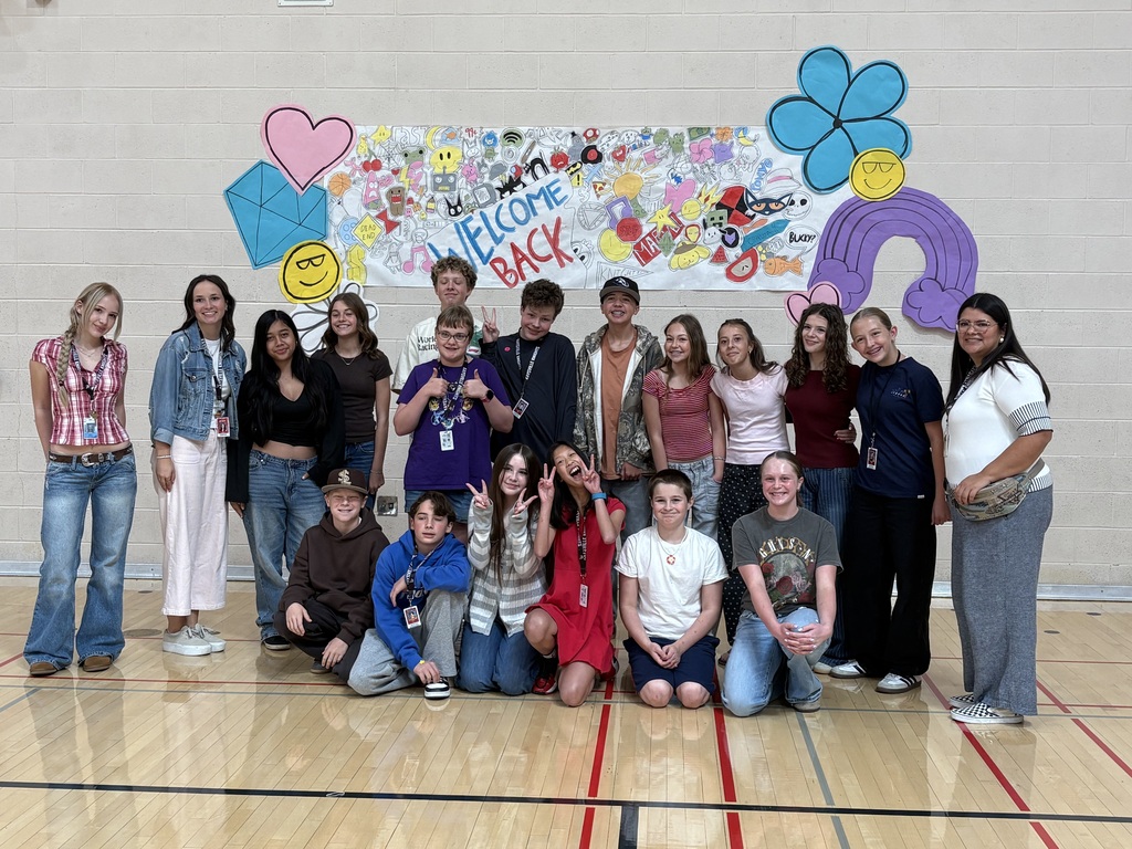 image of students posing for a photo with a banner behind them.
