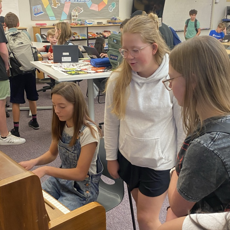 student playing the piano while others listen