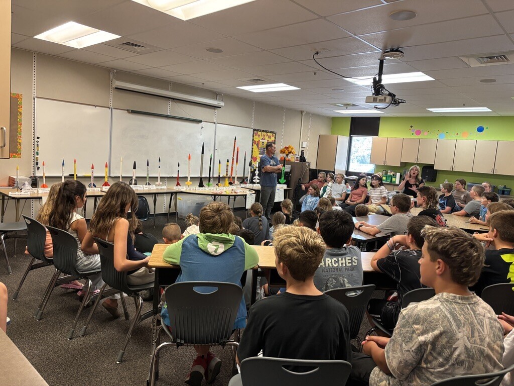 Children gathered around learning about rockets