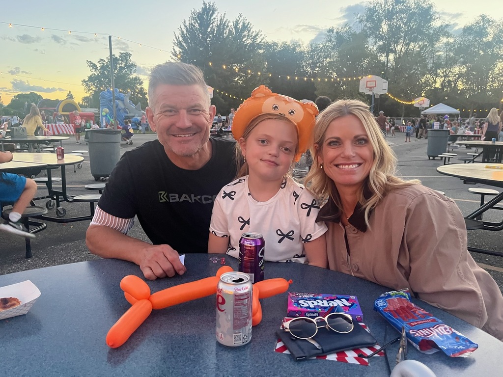 A female student poses with her mom and dad at the school carnival