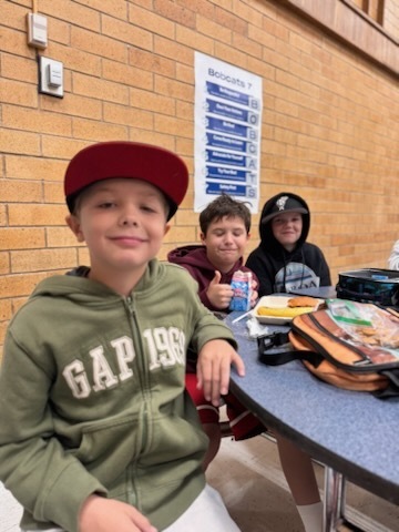 Three 5th grade boys sitting in their elementary school cafeteria