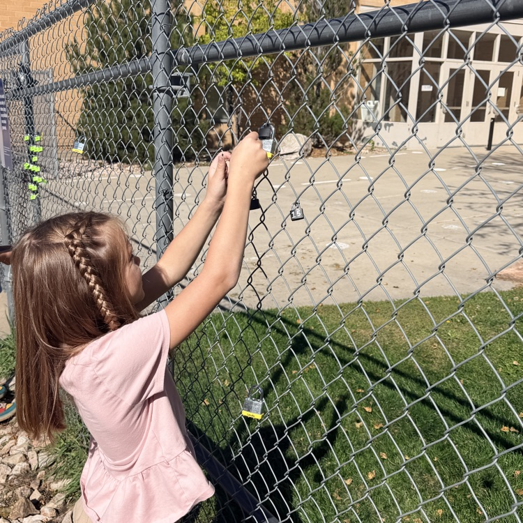 student putting lock up on fence for school and class project