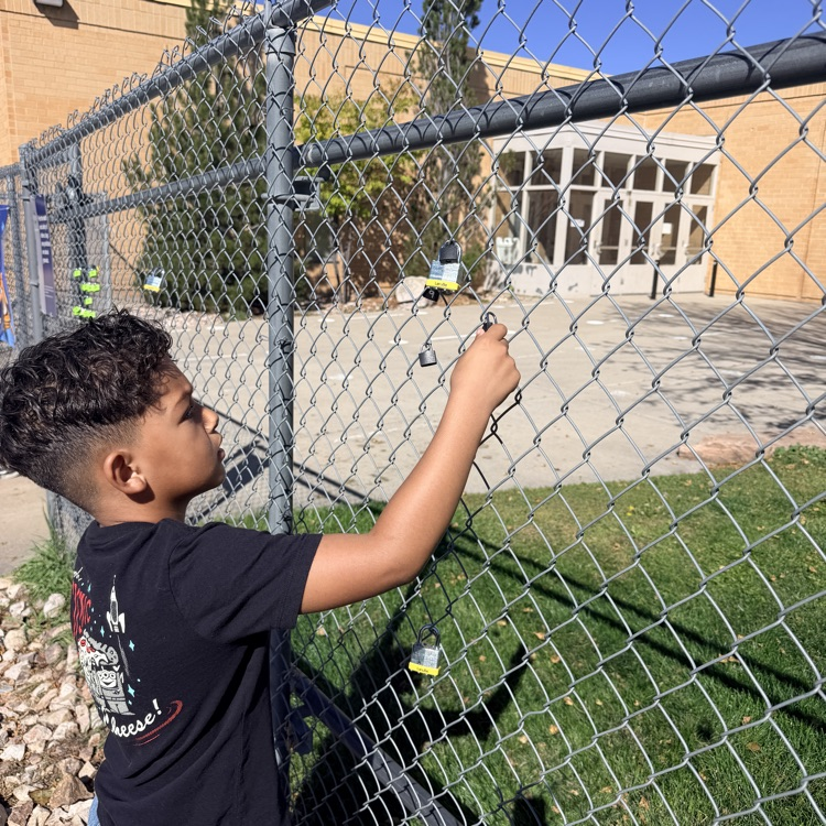 student putting lock up on fence for school and class project