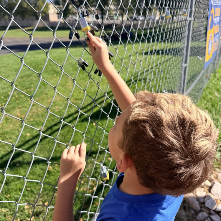 student putting lock up on fence for school and class project