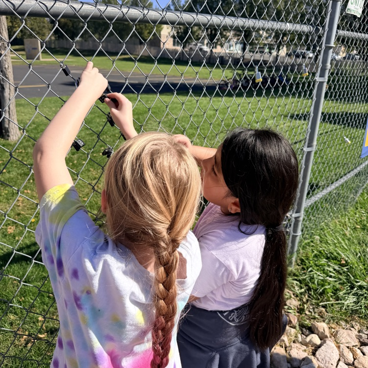 student putting lock up on fence for school and class project