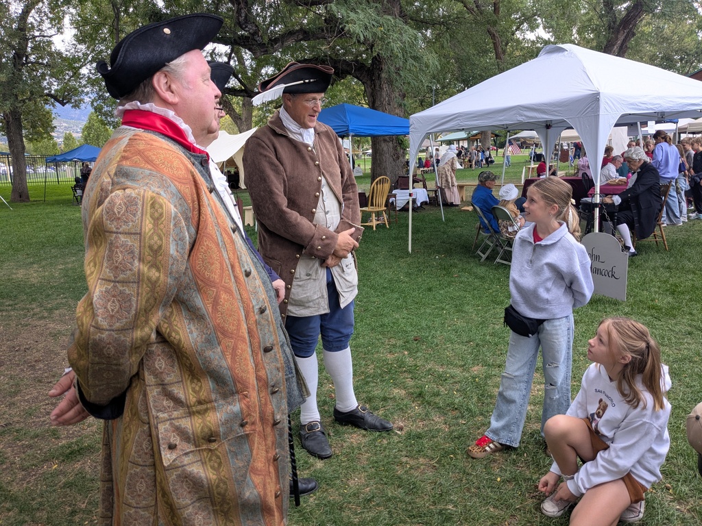 Students talking to men dressed in colonial clothing. 