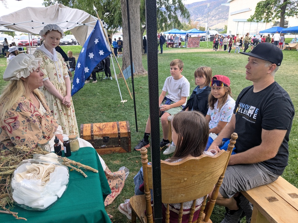 Students listening to ladies in colonial clothing. 
