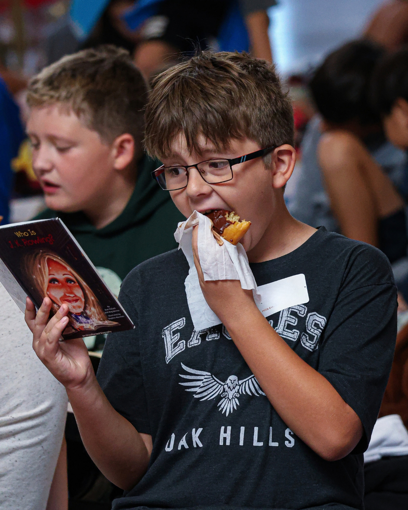 A Davis School District student reading and eating a donut at the Utah Reads Read-A-Thon at the Utah State Capitol. 