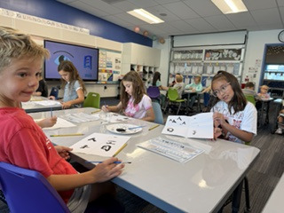 a boy and two girls writing in black ink on white paper