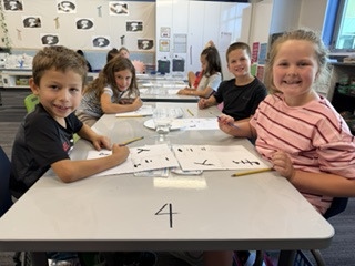 a group a studens around a table with white paper and black ink Chinese characters