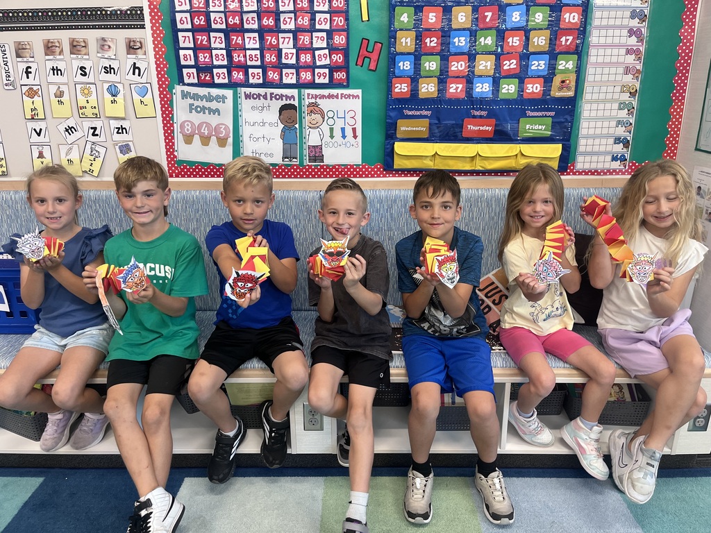 a group of students holding up red and yellow paper Chinese dragons