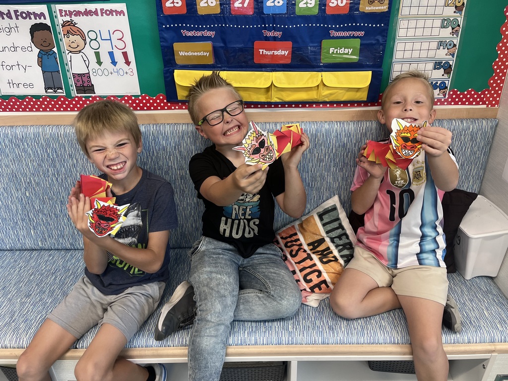 three boys holding up paper dragons