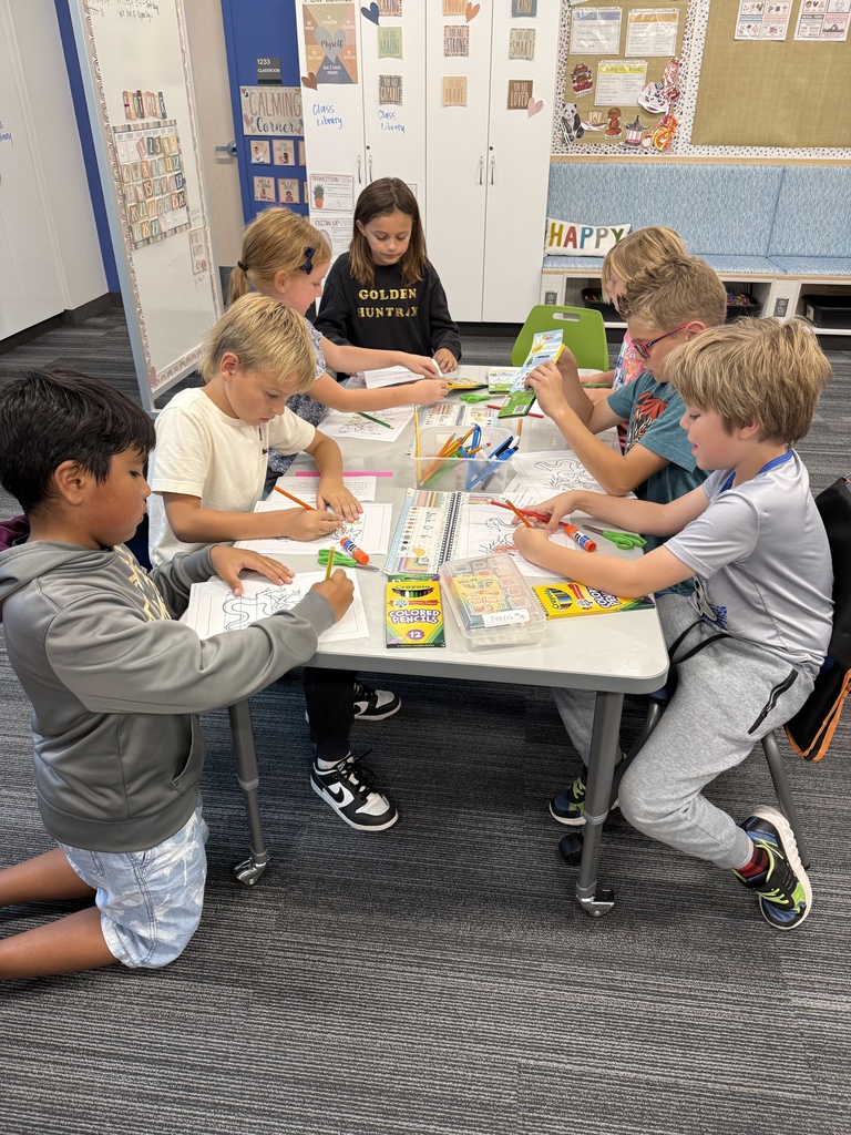 students around a table coloring with colored pencils