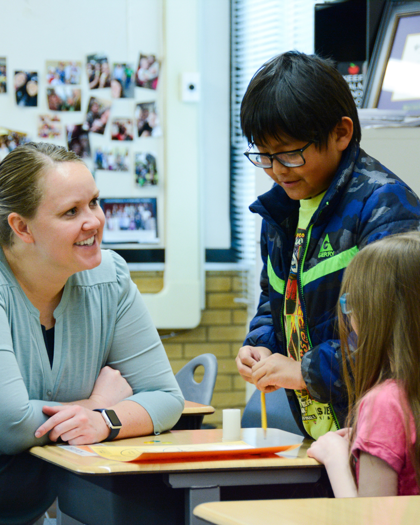 A teacher working with two students on a problem.