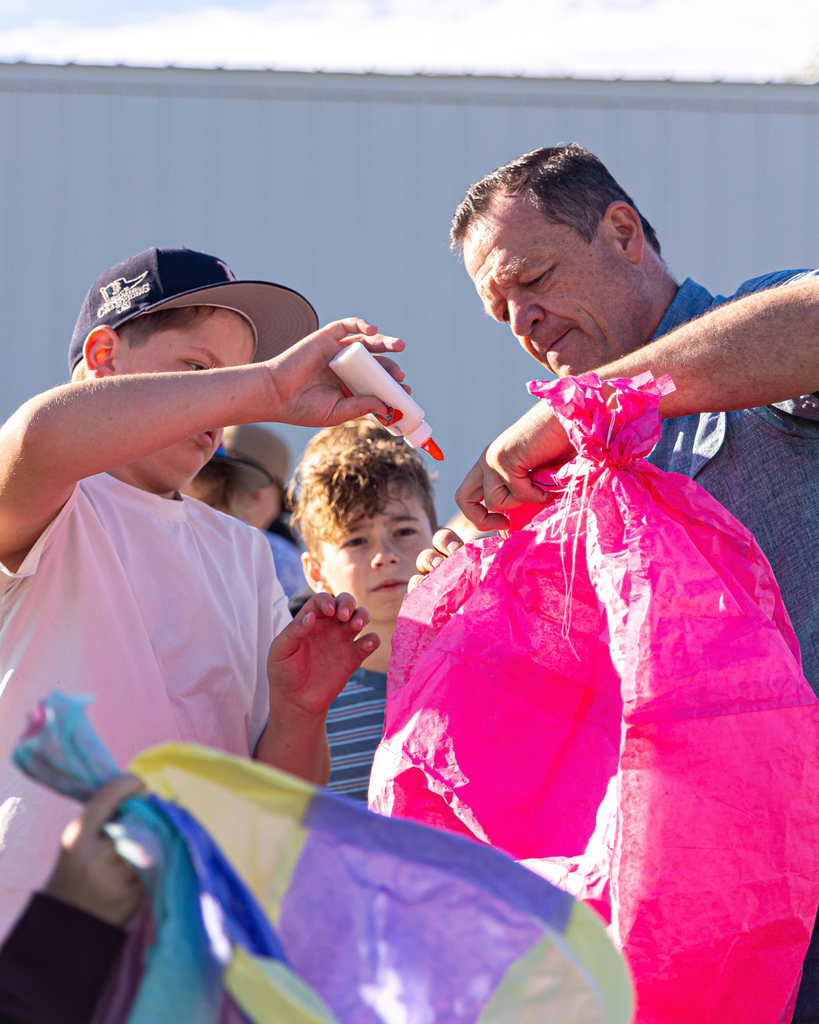 A teacher helps a student glue their hot air balloon together.