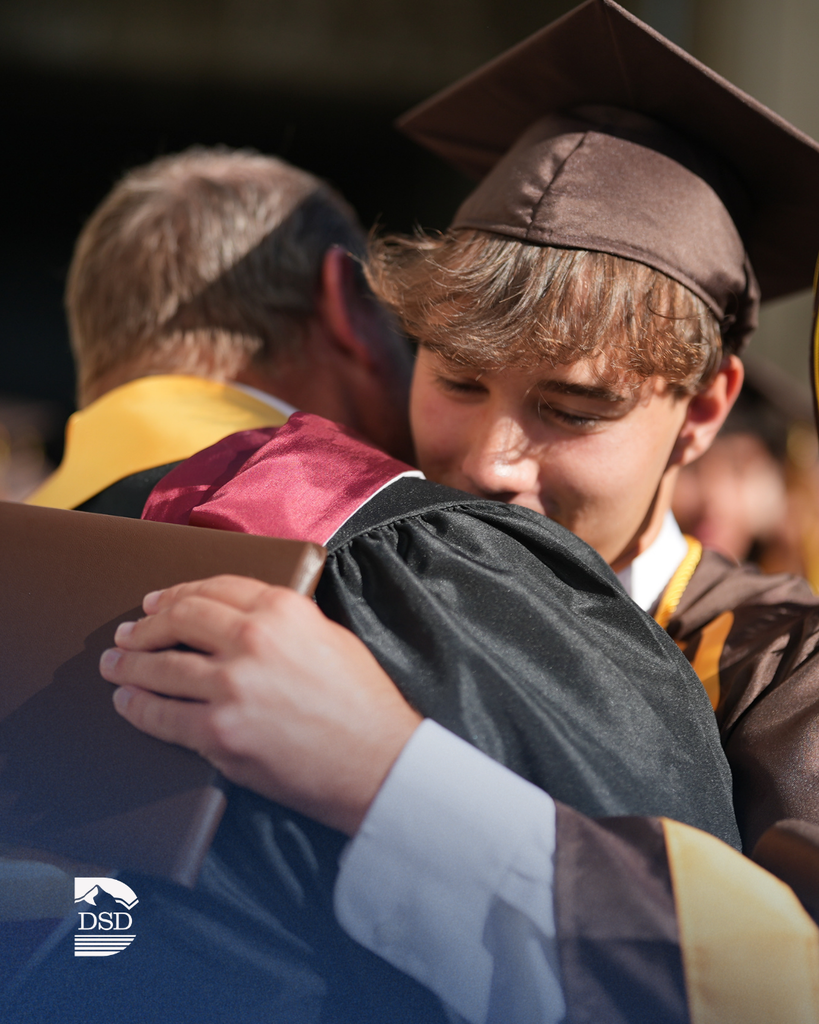 A student hugging a teacher during graduation.