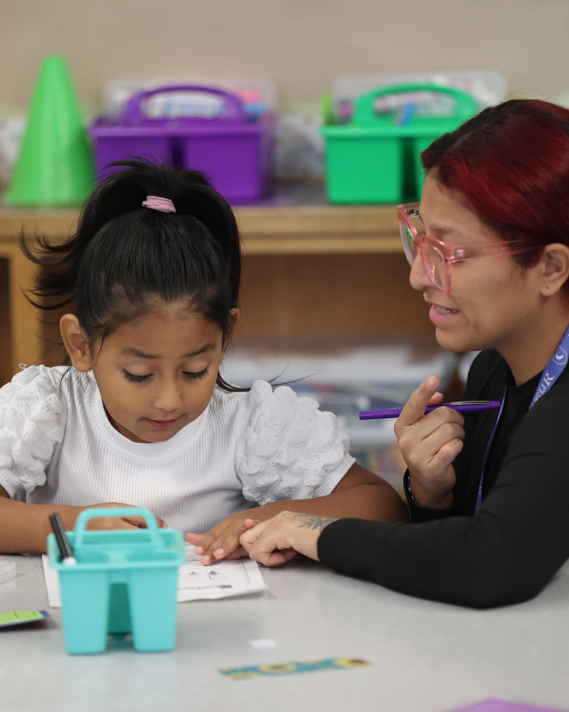 A teacher helps a student with a problem.