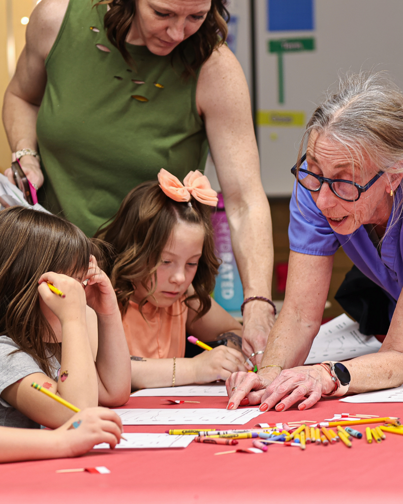 A teacher helps several students with a worksheet. 