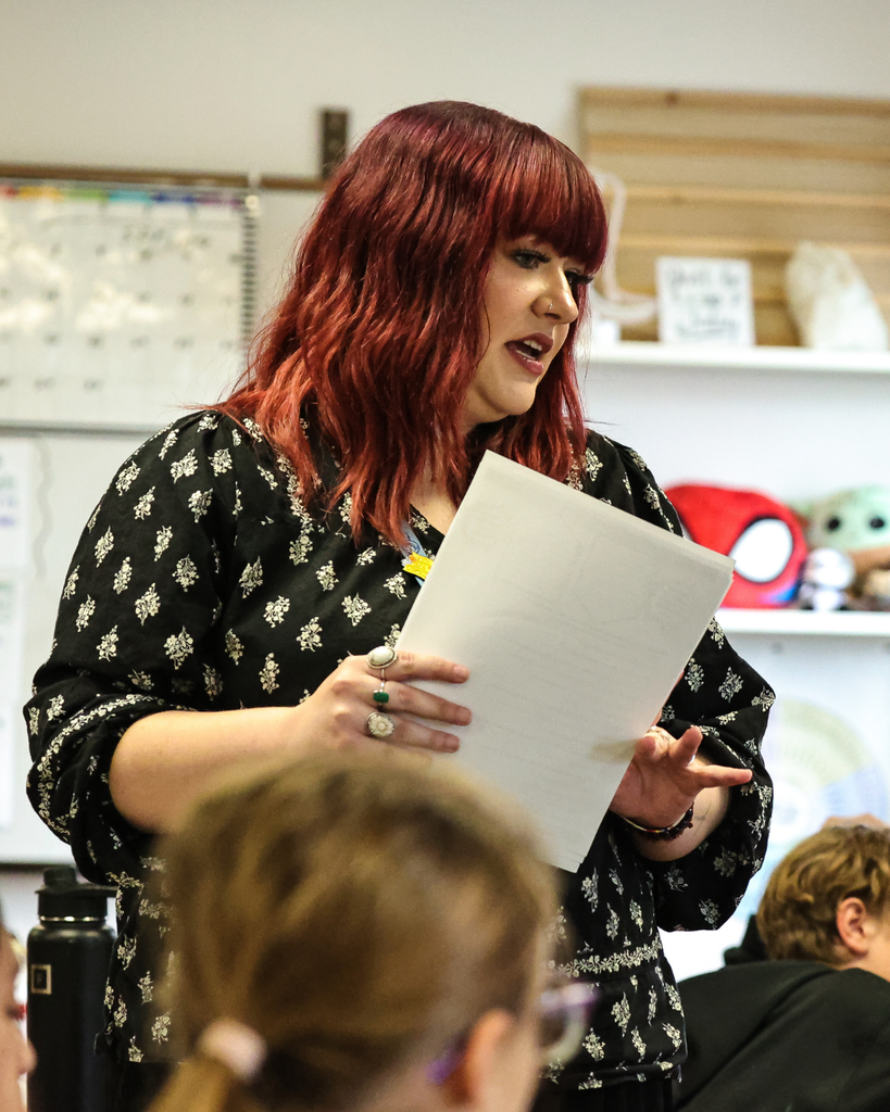 A teacher talks to a group of students during class. 