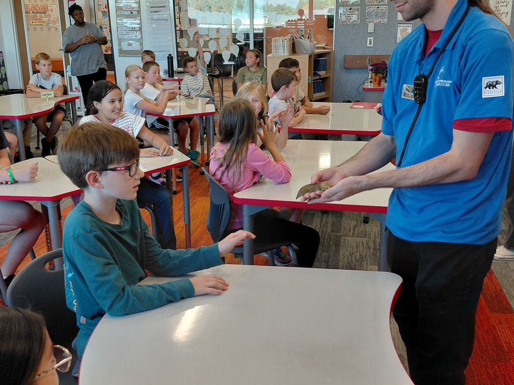 Students looking at a small animal in the hands of a aquarium specalist.