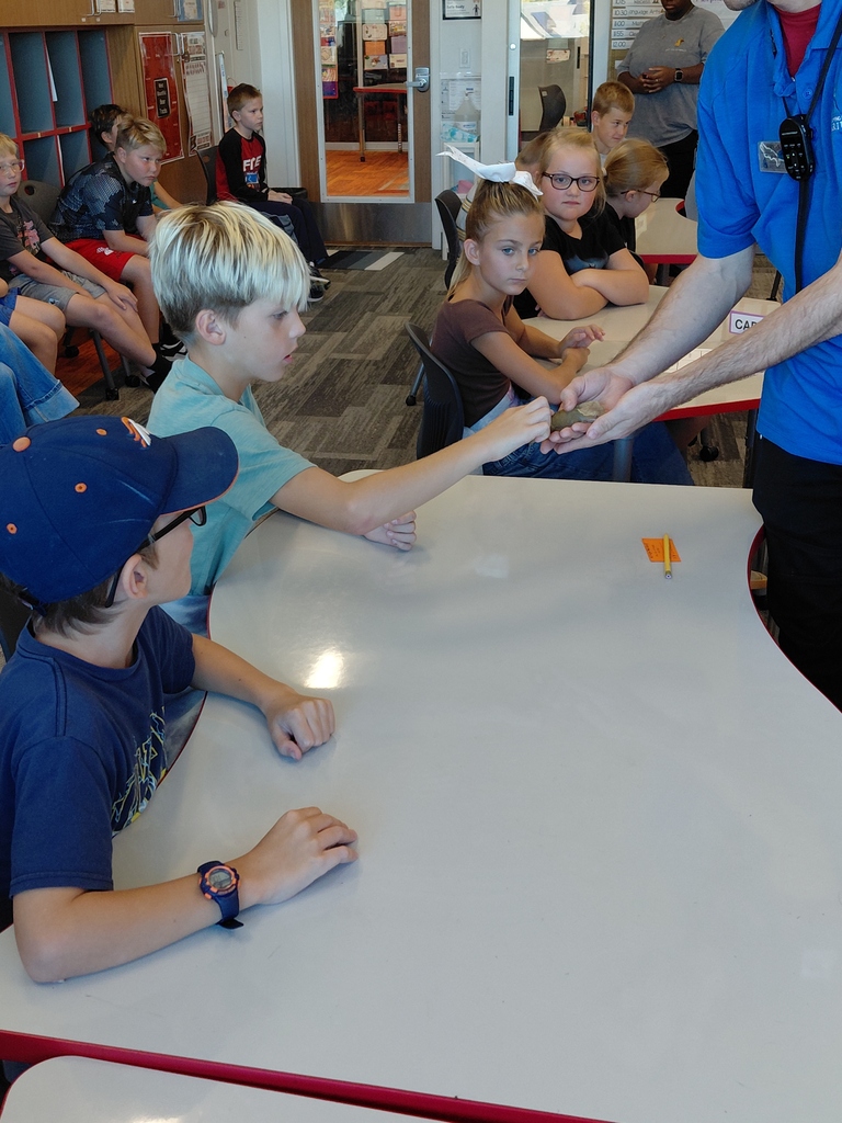Students looking at a small animal in the hands of a aquarium specalist.