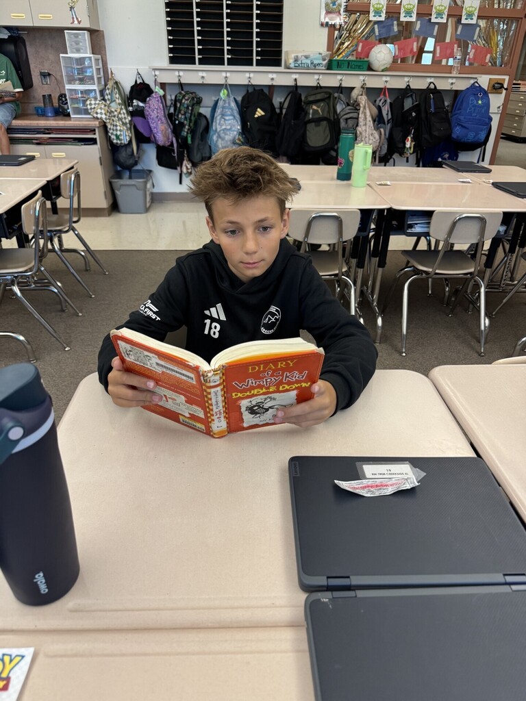 boy reading book in classroom