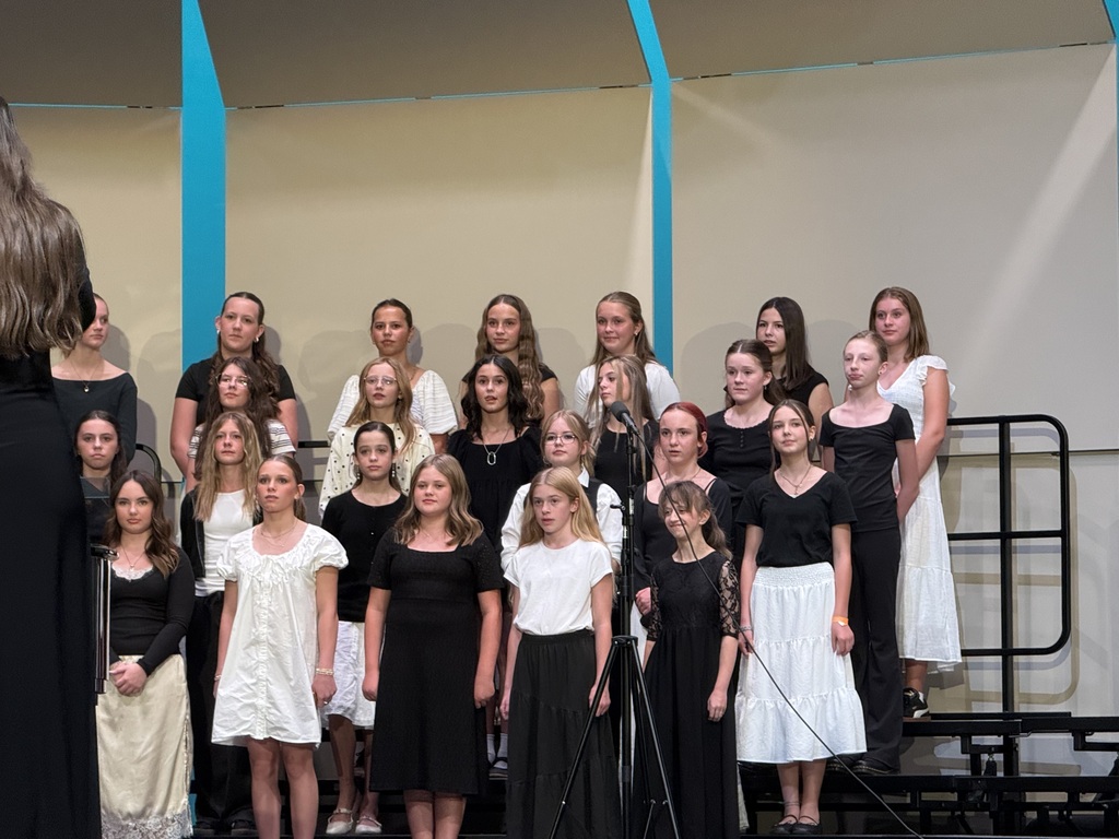 Female choir students performing at the concert wearing various white and black outfits. 