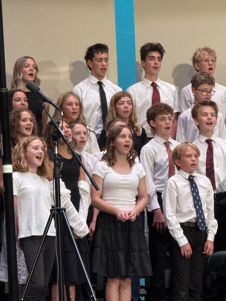 Combined choir singing wearing white shirts and black bottoms. 