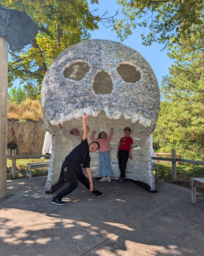Four students pose beneath a large animal-themed structure at Hogle Zoo.