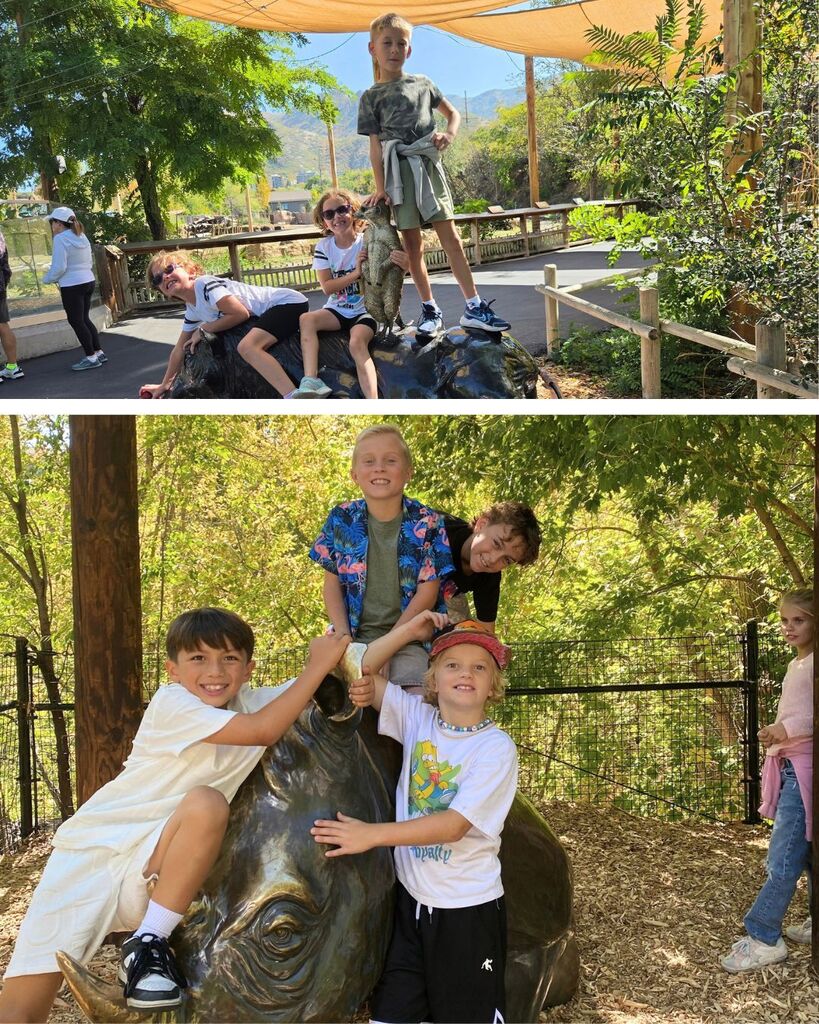 Students smile and pose together on animal statues during their field trip to Hogle Zoo.