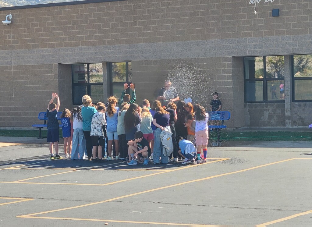 Nr. Nash outside spraying kids with water after being turned into an ice cream sundae
