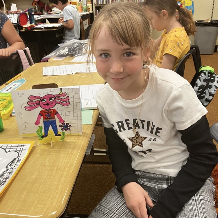 3rd grader displaying their creative and background they created during their specials BTS class