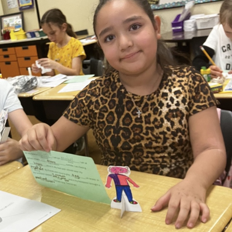 3rd grader displaying their creative and background they created during their specials BTS class