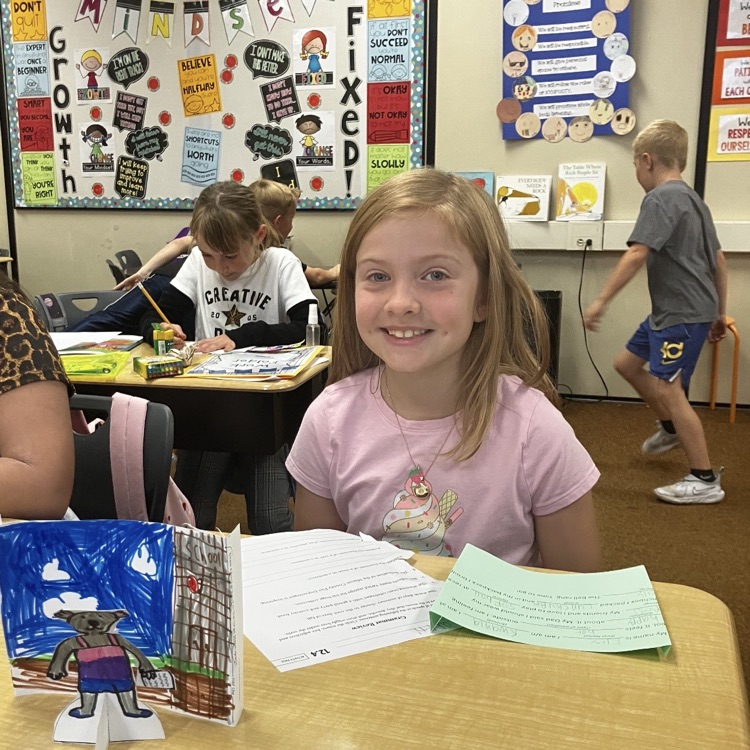 3rd grader displaying their creative and background they created during their specials BTS class