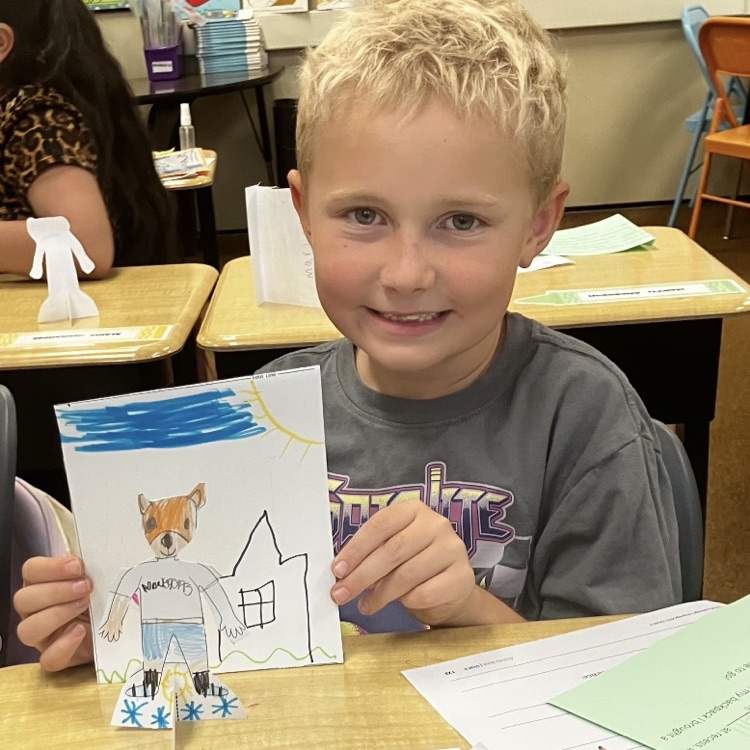 3rd grader displaying their creative and background they created during their specials BTS class