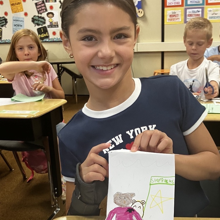 3rd grader displaying their creative and background they created during their specials BTS class