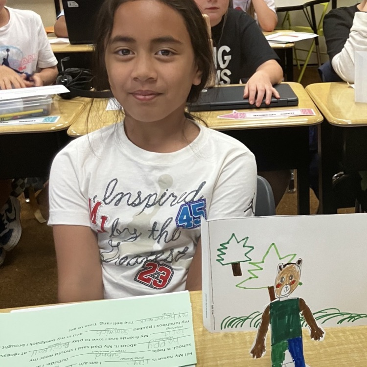 3rd grader displaying their creative and background they created during their specials BTS class