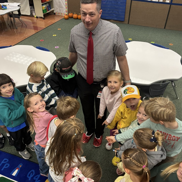Principal wearing ruby slippers standing in a group of students  