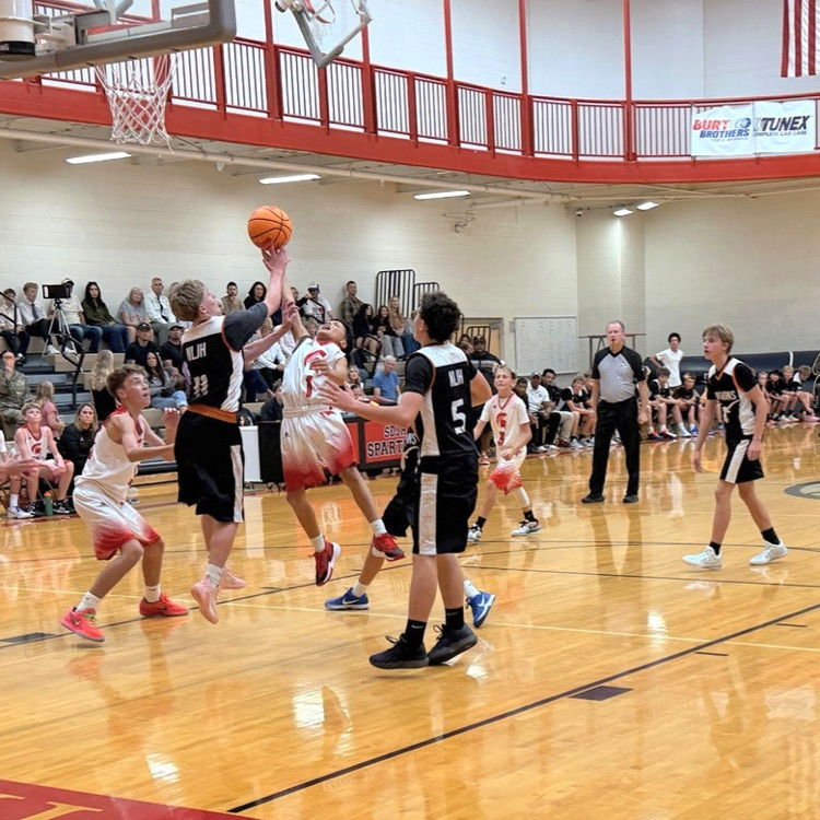 Players jump for the basketball during a boys basketball game at South Davis Junior High.
