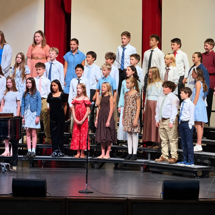 Beginning choir students perform on risers in their concert attire.
