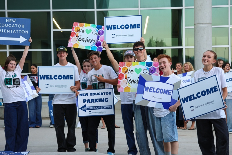 Students smile as they hold welcome and we love our teachers signs. 
