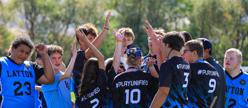 A team of students celebrating and raising up their arms.