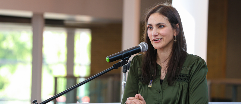 An adult speaking into a microphone and smiling.