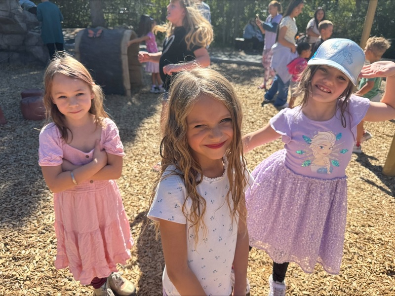 Three students pose on the playground.