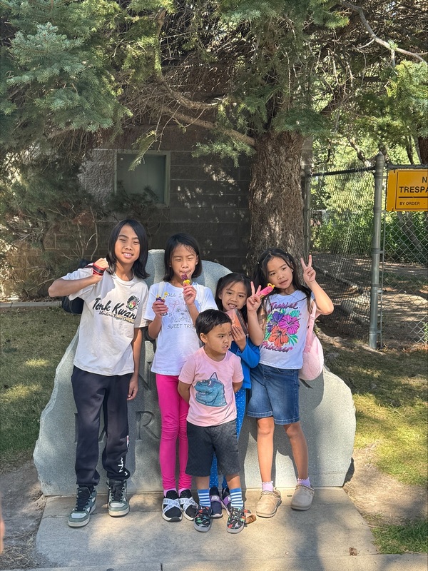 Five students pose in front of the Dinosaur Park sign.